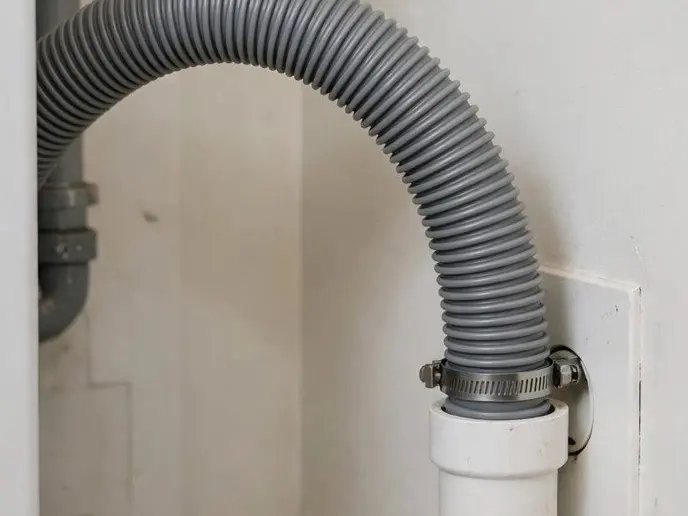 A washer drain hose curving into a laundry standpipe